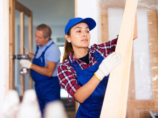Skillful hispanic woman builder carrying wooden planks. Home improvement works in apartment.