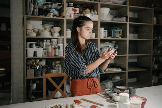 A pottery artist examining a ceramic piece in a workshop studio