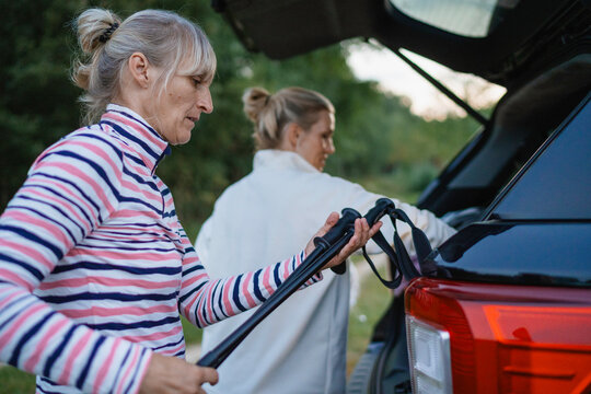 The women are going to put trekking poles in the car trunk