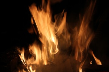 Fototapeta premium Bright golden orange flames against black background with copy space