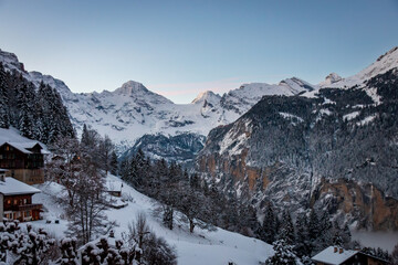 Scenic view of Lauterbrunnen Valley, Switzerland seen from Wengen with snowcovered mountains with Breithorn (left) and Tschingelhorn (right) in winter against blue sky at sunset
