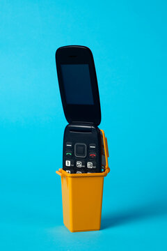 clamshell mobile phone in the trash container