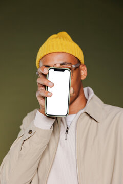 Stylish man covering his face with smartphone showing empty screen