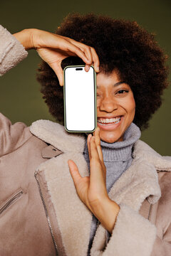 Woman smiling and showing smartphone with empty screen
