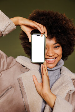 Woman smiling and showing smartphone with empty screen