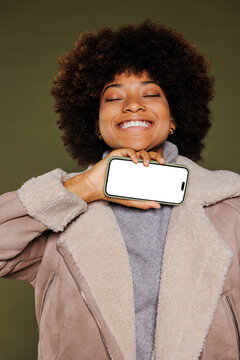 Woman holding smartphone under chin with closed eyes
