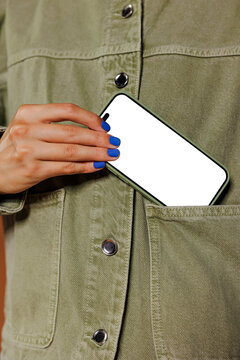 Woman putting smartphone with blank screen in denim jacket pocket