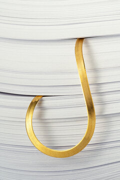 Gold chain stack between pile of papers