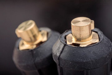 Close-up of cable plugs of an electrode holder and grounding clamp from a welding inverter machine, showing fine details of industrial connections.