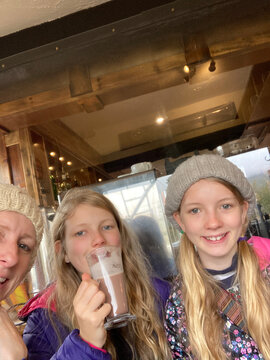 A mum and daughters drink hot chocolate indoors
