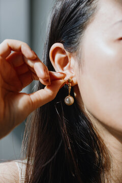 Woman wearing pearl drop earrings with gold accents