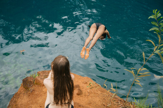 Two Women Diving into a Blue Lagoon from a Cliff