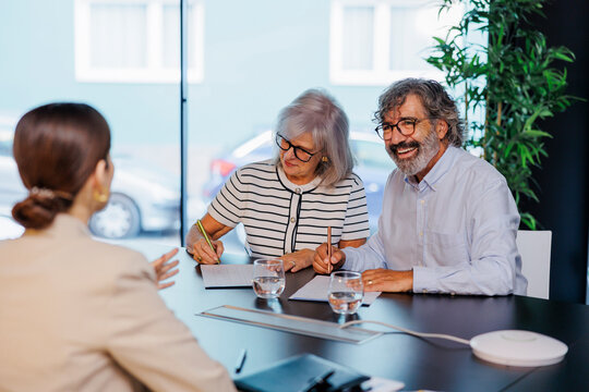 Senior couple smiling while signing contract with financial advisor