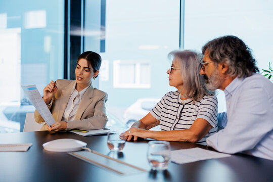 Financial advisor explaining documents to senior couple in meeting