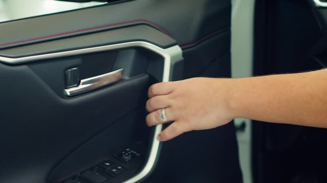 Close up shot of person closing car after using lock controls on panel to unlock it. Automobile owner pulling door handle after using buttons to disengage mechanism latch