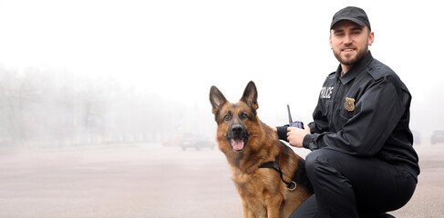 Male police officer with dog patrolling city street