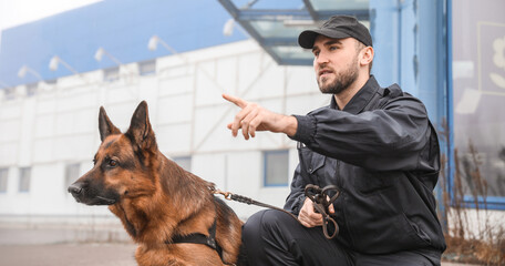 Male police officer with dog patrolling city street