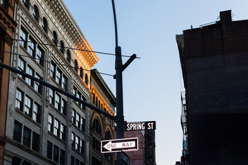 A street name sign next to a one-way indication on a power pole