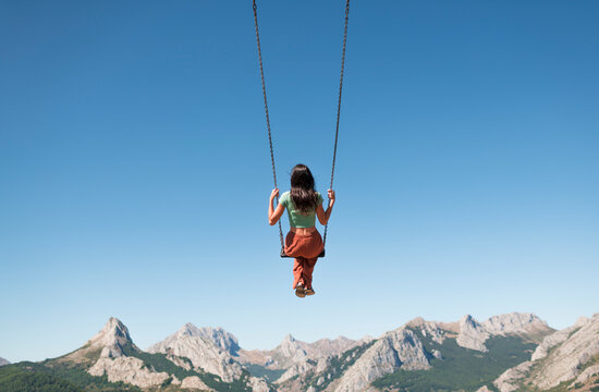 Swinging woman enjoying peaceful mountain view