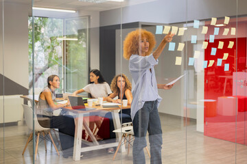 Team brainstorming session with sticky notes on office glass wall