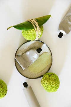 Green fruits and cosmetics lying on a white background 