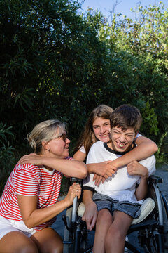 Woman and teenage girl with disabled child outdoors