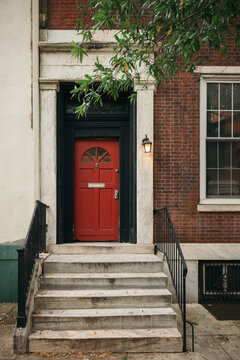 red door with black framing and stone steps in front of a brick house