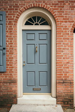 Brick townhouse with a light blue door and arched window.
