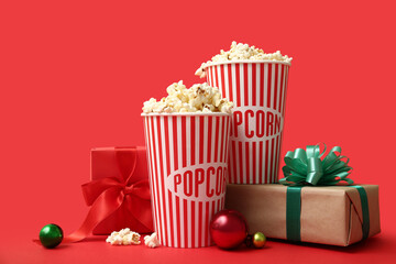 Buckets of popcorn with gifts and Christmas balls on red background