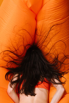 Woman Relaxing on Orange Inflatable Lounger with Hair Spread Out