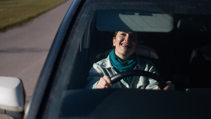 Caucasian woman sitting behind the wheel and looking in the mirror. 