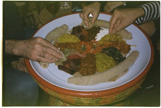 people eating Ethiopian food from the same tray, 35mm