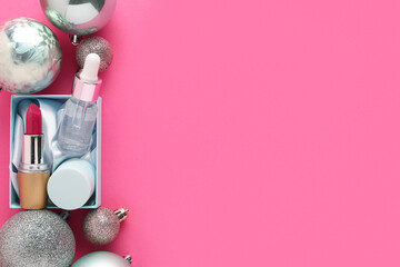 Cosmetic products with Christmas balls on pink background. Top view