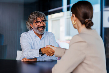 Senior man shaking hands with financial advisor in meeting