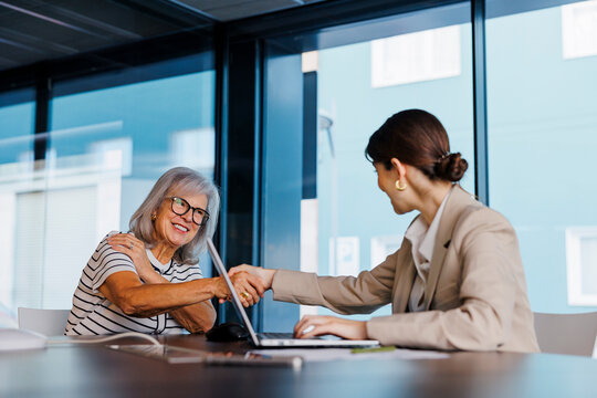 Senior woman shaking hands with financial advisor in meeting - Powered by Adobe