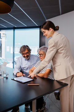 Financial advisor showing contract on tablet to senior couple