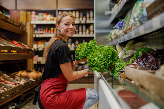 A cheerful and friendly grocer carefully arranges an array of fresh herbs in a lively, inviting market setting - Powered by Adobe