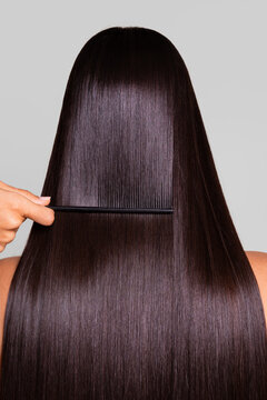 Woman having her long, straight, dark hair combed with a black comb