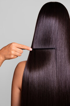Woman having her long, dark, shiny hair combed with a black comb