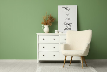 Interior of living room with commode, poster and armchair