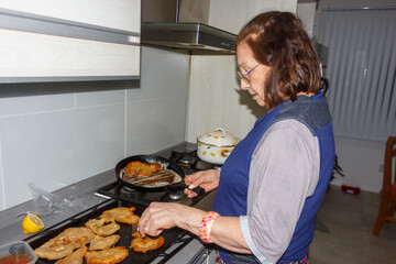 Grandmother cooking crispy milanesas in the kitchen