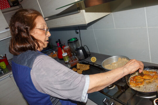 Grandmother cooking crispy milanesas in the kitchen