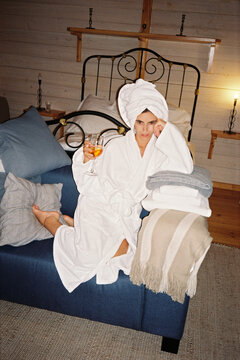 Woman with bathrobe and glass of wine in her bedroom
