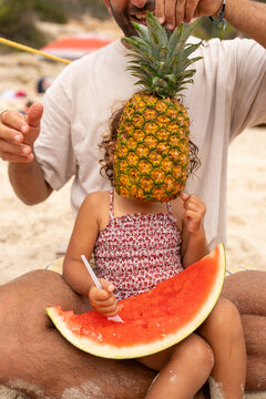 Dad holding a pineapple in front of his toddler for fun
