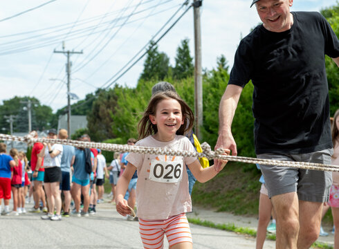 Happy child crosses the finish line with her Dad during a running race