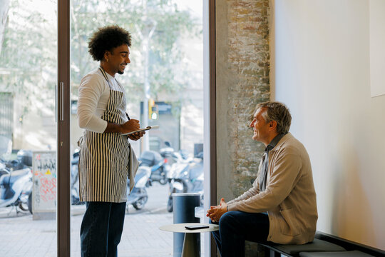 Waiter taking order from a customer sitting at bench