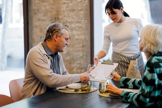 Couple ordering food from a waitress in a restaurant