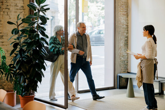 Couple entering restaurant greeted by waitress
