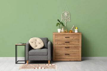 Interior of living room with armchair and decorative pumpkins on commode