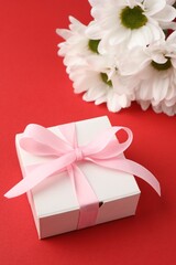 Gift box with bow and flowers on red background